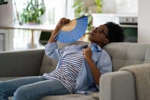 Woman on sofa using paper fans